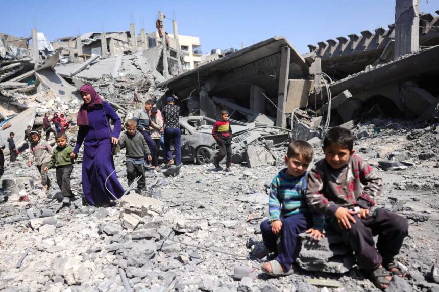 TOPSHOT - Children look on as people walk amid the rubble of a building destroyed in an Israeli strike in Jabalia, in the northern Gaza Strip (Photo by Getty Images)
